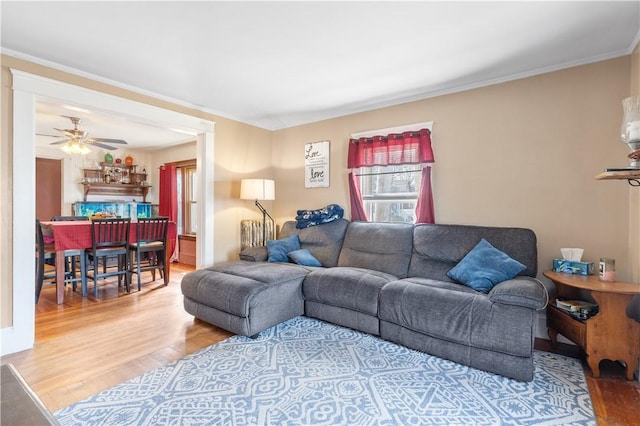 living area with wood finished floors, ceiling fan, and ornamental molding