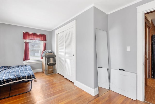 bedroom featuring crown molding, a closet, wood finished floors, and baseboards