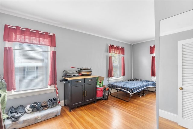 bedroom with ornamental molding, light wood-style flooring, and multiple windows