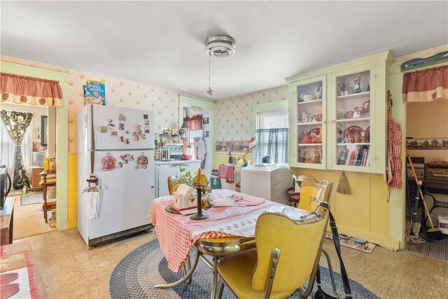 dining area featuring light floors, washer / clothes dryer, and wallpapered walls