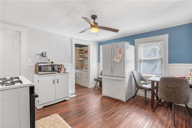 kitchen with stainless steel microwave, range with gas stovetop, ceiling fan, wainscoting, and freestanding refrigerator