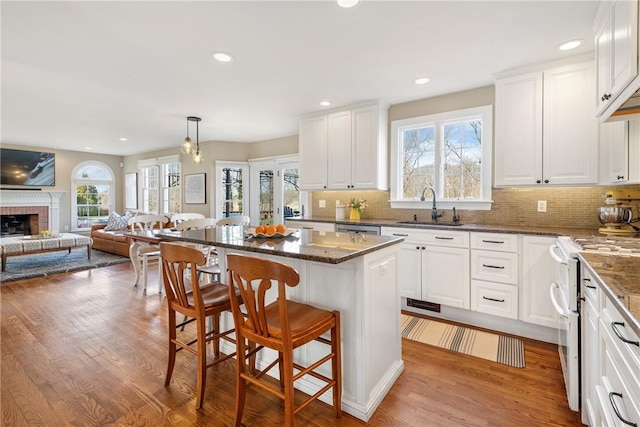 kitchen featuring a sink, open floor plan, white range with electric cooktop, and wood finished floors