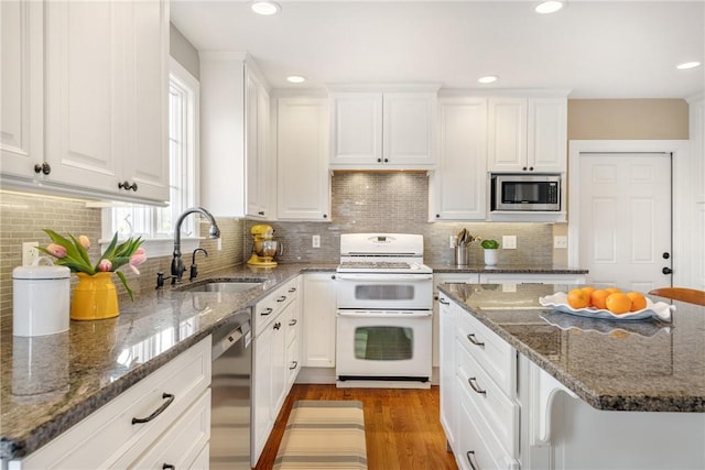 kitchen with a sink, white cabinets, appliances with stainless steel finishes, and dark stone countertops
