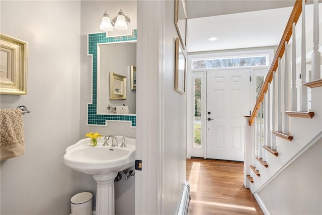 bathroom featuring a baseboard heating unit, a sink, and wood finished floors