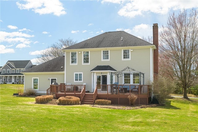 back of property featuring a shingled roof, a chimney, a wooden deck, and a yard
