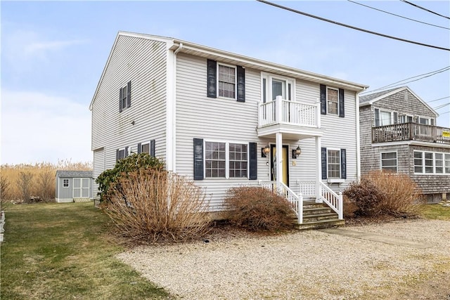 view of front of property with a storage shed, an outbuilding, a balcony, and a front yard