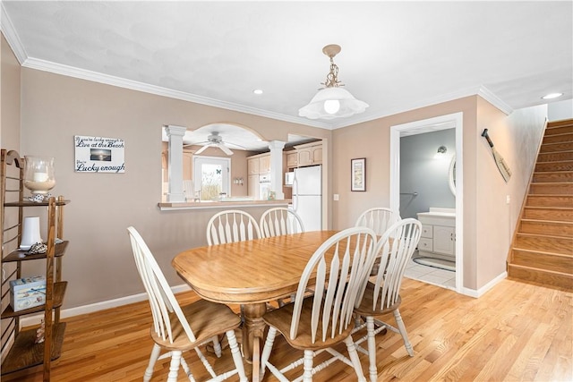 dining room featuring stairway, baseboards, light wood-style flooring, and ornate columns