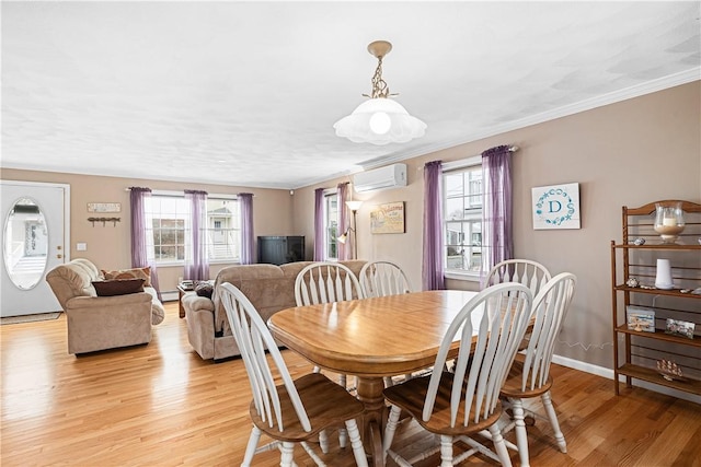 dining space with baseboards, light wood finished floors, a wall unit AC, and ornamental molding