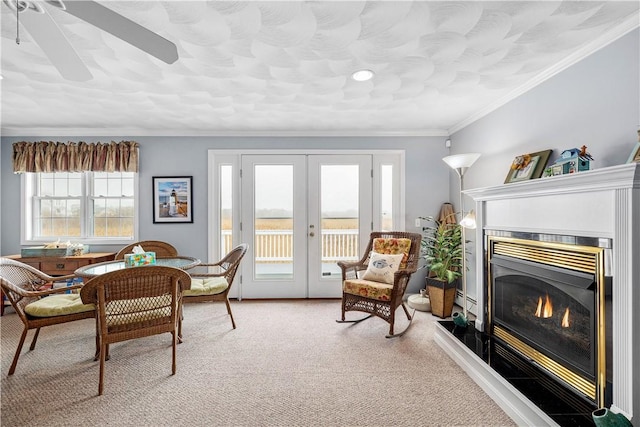 interior space featuring light carpet, french doors, a ceiling fan, a fireplace, and ornamental molding