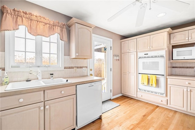 kitchen featuring plenty of natural light, light countertops, white appliances, and a sink