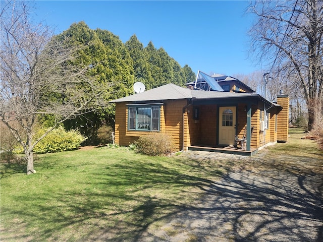 view of front of property with a porch, a front yard, and a chimney