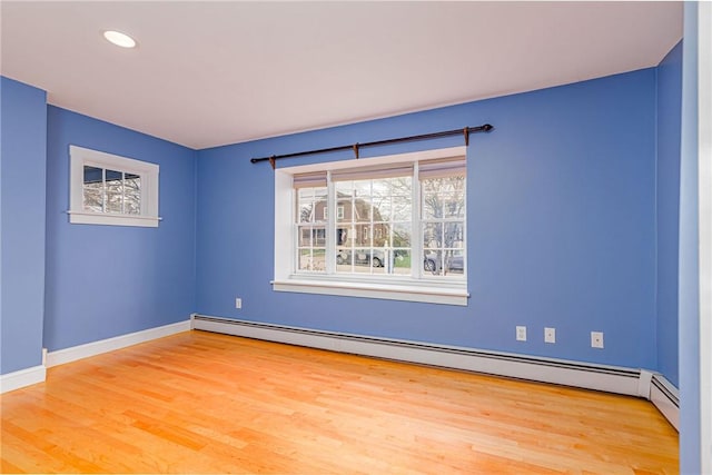 empty room featuring a baseboard heating unit, baseboards, wood finished floors, and recessed lighting