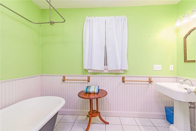 bathroom featuring a freestanding tub, tile patterned flooring, baseboards, and wainscoting
