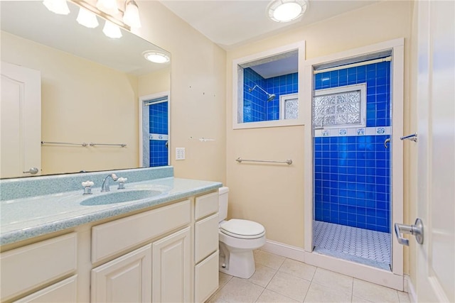 bathroom featuring vanity, a tile shower, toilet, and tile patterned flooring