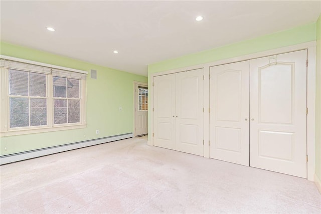 unfurnished bedroom featuring light carpet, multiple closets, recessed lighting, and a baseboard radiator