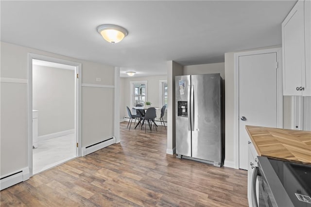kitchen with appliances with stainless steel finishes, baseboard heating, white cabinetry, wood counters, and wood finished floors