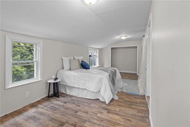 bedroom with wood finished floors, baseboards, and lofted ceiling