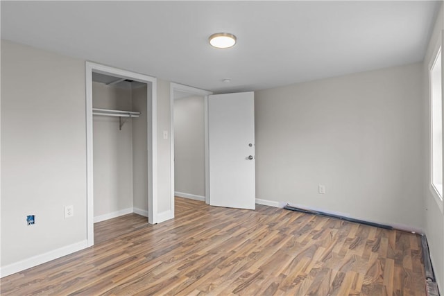 unfurnished bedroom featuring wood finished floors, baseboards, and a closet