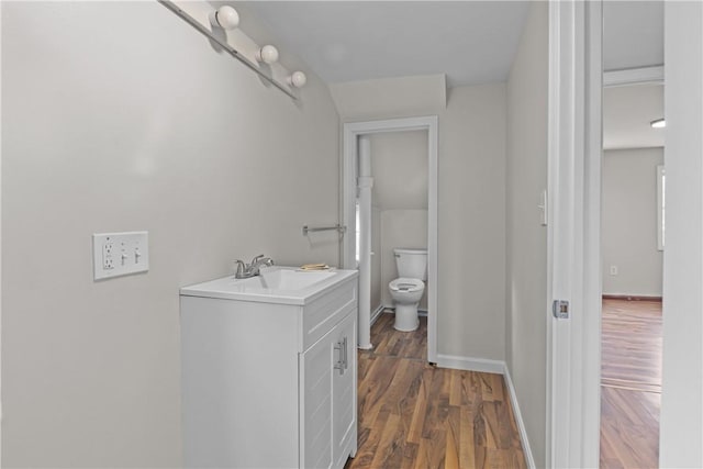 bathroom with toilet, wood finished floors, vanity, and baseboards