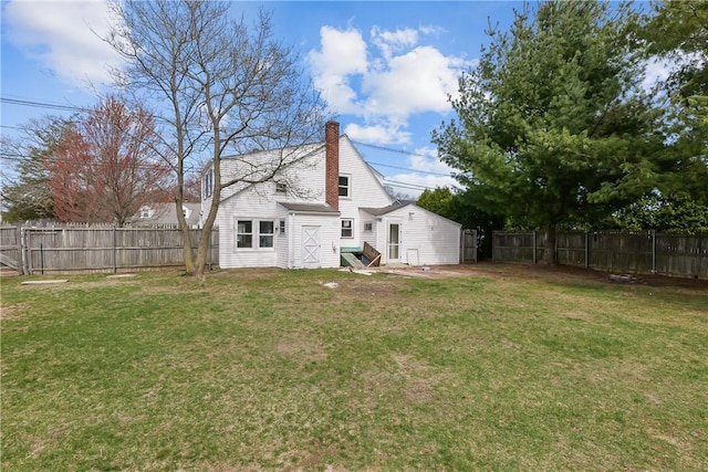 rear view of property featuring a yard, a fenced backyard, and a chimney