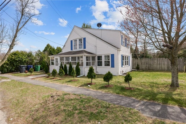 view of front of home featuring a front lawn, fence, and a sunroom