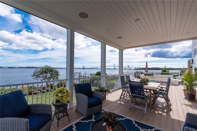 wooden terrace featuring outdoor dining area, a water view, and an outdoor hangout area