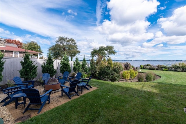view of yard featuring fence, a patio, an outdoor fire pit, and a water view