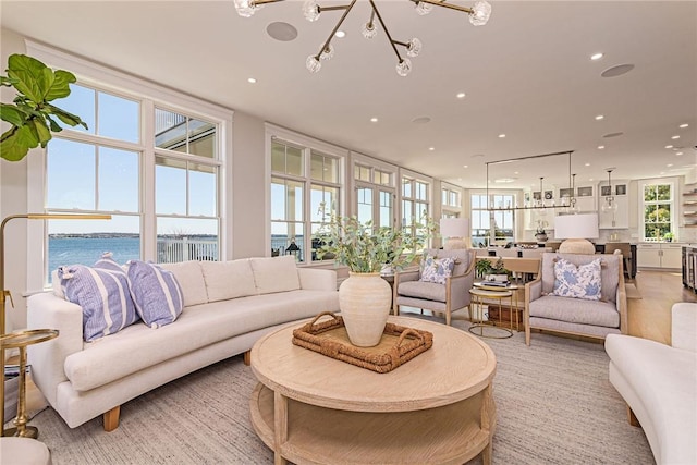 living room with a chandelier, a water view, and recessed lighting