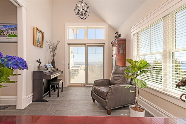 sitting room with plenty of natural light, lofted ceiling, baseboards, and an inviting chandelier