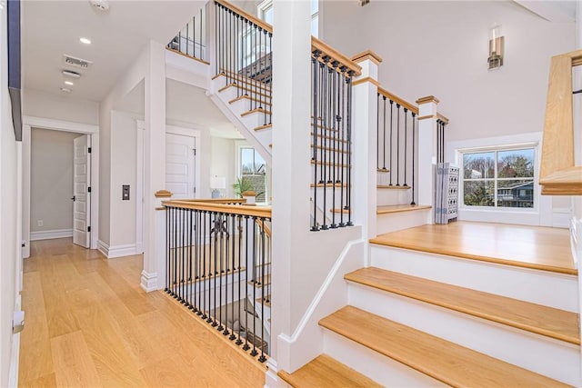 stairs with recessed lighting, wood finished floors, a towering ceiling, and baseboards