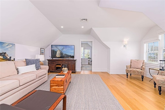 living room with light wood finished floors, baseboards, lofted ceiling, visible vents, and recessed lighting