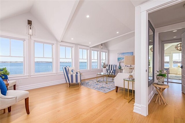 sitting room with lofted ceiling, baseboards, light wood-style floors, and a water view