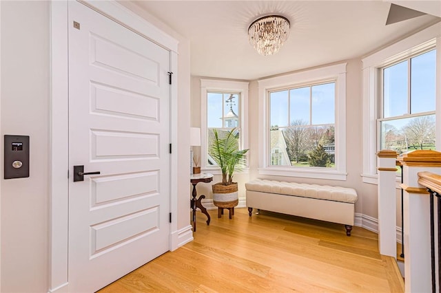 living area featuring a notable chandelier, baseboards, and light wood-style floors