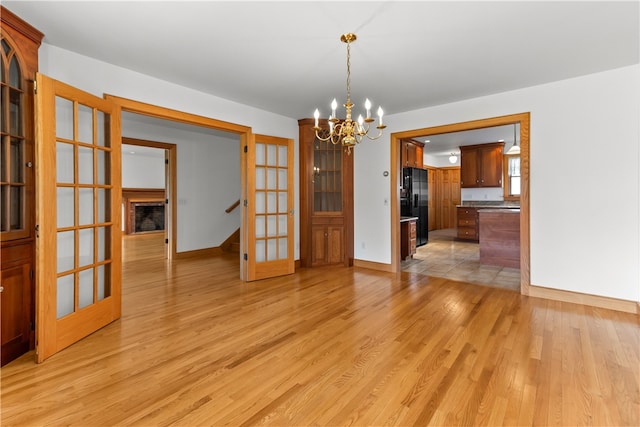 200 Pond St, South Kingstown, RI 02879 - unfurnished dining area featuring light wood-style floors, stairs, french doors, a notable chandelier, and baseboards