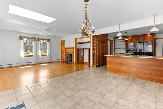 200 Pond St, South Kingstown, RI 02879 - kitchen featuring hanging light fixtures, ceiling fan, appliances with stainless steel finishes, a fireplace, and a skylight