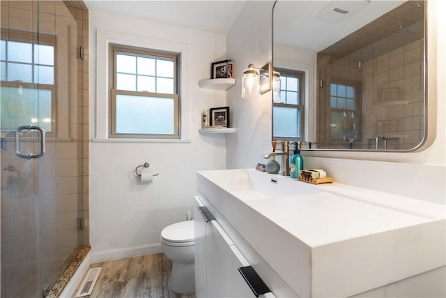 bathroom with visible vents, a wealth of natural light, a stall shower, and wood finished floors
