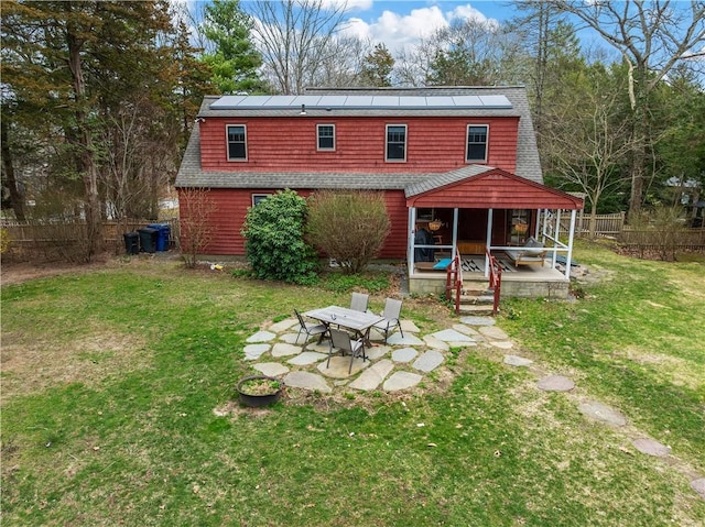back of house with a patio area, solar panels, and a lawn