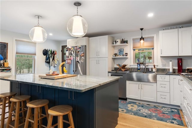 kitchen featuring appliances with stainless steel finishes, a kitchen island, white cabinets, a healthy amount of sunlight, and a sink
