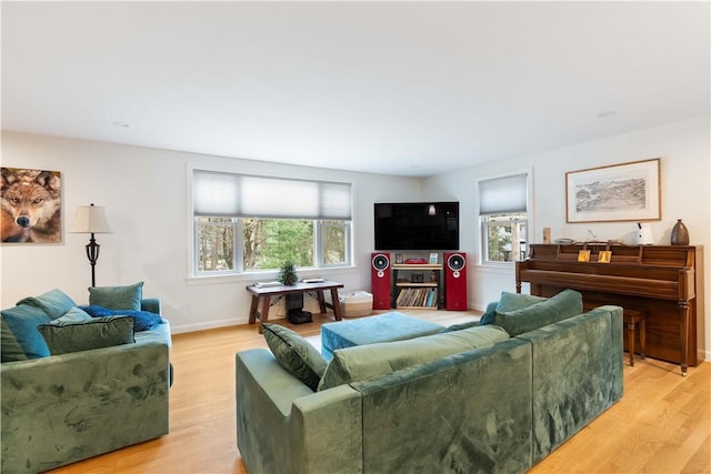 living room featuring light wood-style flooring, baseboards, and plenty of natural light