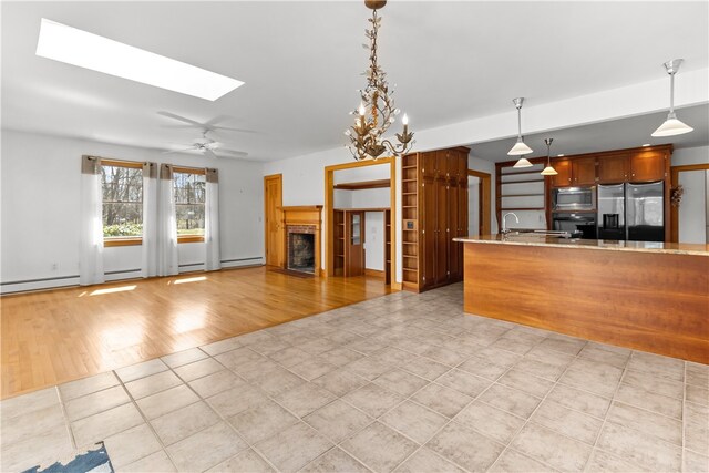 200 Pond St, South Kingstown, RI 02879 - kitchen featuring pendant lighting, a fireplace, a ceiling fan, a skylight, and stainless steel appliances