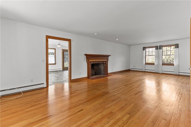 200 Pond St, South Kingstown, RI 02879 - unfurnished living room with baseboard heating, a fireplace with flush hearth, light wood finished floors, and a ceiling fan