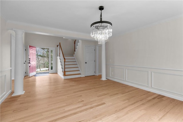 unfurnished dining area with a chandelier, stairway, crown molding, a decorative wall, and light wood finished floors