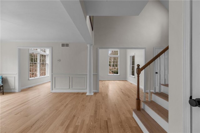 entryway with light wood-style flooring, a wainscoted wall, stairs, visible vents, and a decorative wall