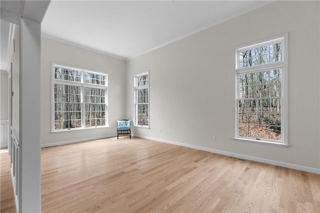 spare room with light wood finished floors, visible vents, baseboards, and ornamental molding