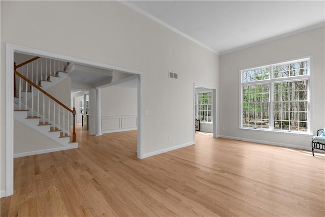 unfurnished living room featuring ornamental molding, visible vents, stairs, light wood finished floors, and baseboards