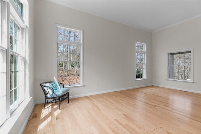 unfurnished room featuring light wood-style flooring, a healthy amount of sunlight, baseboards, and ornamental molding