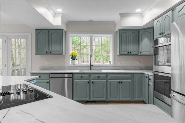 kitchen with a sink, ornamental molding, appliances with stainless steel finishes, and green cabinetry