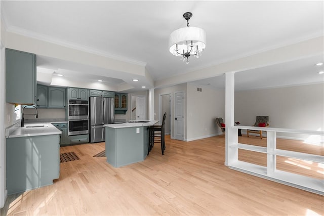 kitchen with light wood-style flooring, appliances with stainless steel finishes, a breakfast bar area, and light countertops