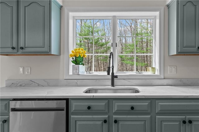 kitchen featuring stainless steel dishwasher, a sink, and gray cabinets