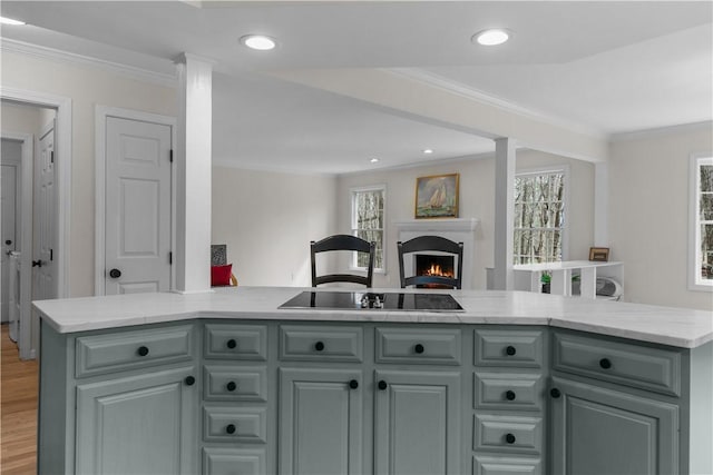 kitchen with light wood-style floors, crown molding, a lit fireplace, recessed lighting, and open floor plan